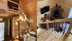 A wooden cabin interior with a staircase, a fireplace, and a television.