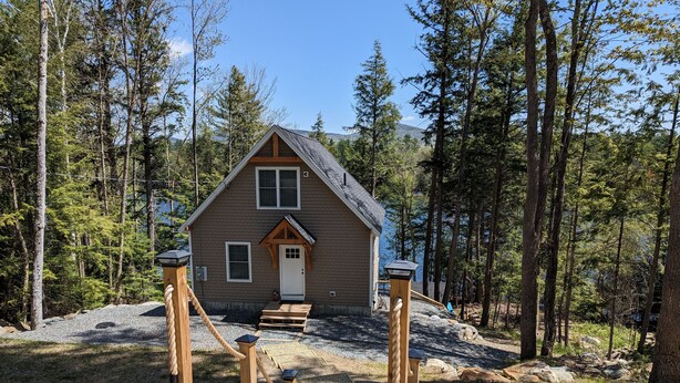 A cabin with a wooden deck and a rope ladder leading to a wooden door.