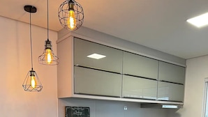 A modern kitchen with a black countertop, grey cabinets, and a black bar stool. - Ap Gold Coast Vista Mar - Piçarras - SC (Picarras)