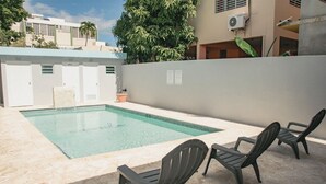 A swimming pool with a tiled edge, surrounded by a low wall and three plastic chairs. - SUITE 203 - 2 PEOPLE (Cabo Rojo)