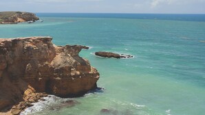 A coastal landscape with a prominent cliff and clear turquoise waters. - SUITE 203 - 2 PEOPLE (Cabo Rojo)