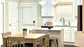A kitchen with white cabinets, a central island, and pendant lighting. - Luxury Townhouse Near Lakefront & Downtown (Lake Charles)