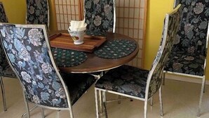 A round dining table with floral-patterned chairs, a wooden tray, and a white napkin holder. - Gypsywind Home (Edmonton)