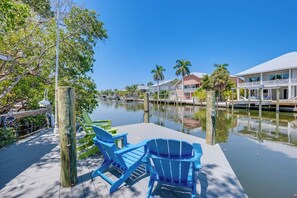 A waterfront property with a dock, blue chairs, and a clear view of the water.