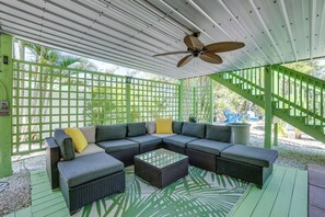 A covered outdoor seating area with a sectional sofa, a coffee table, and a ceiling fan. - Simpatico (Anna Maria)