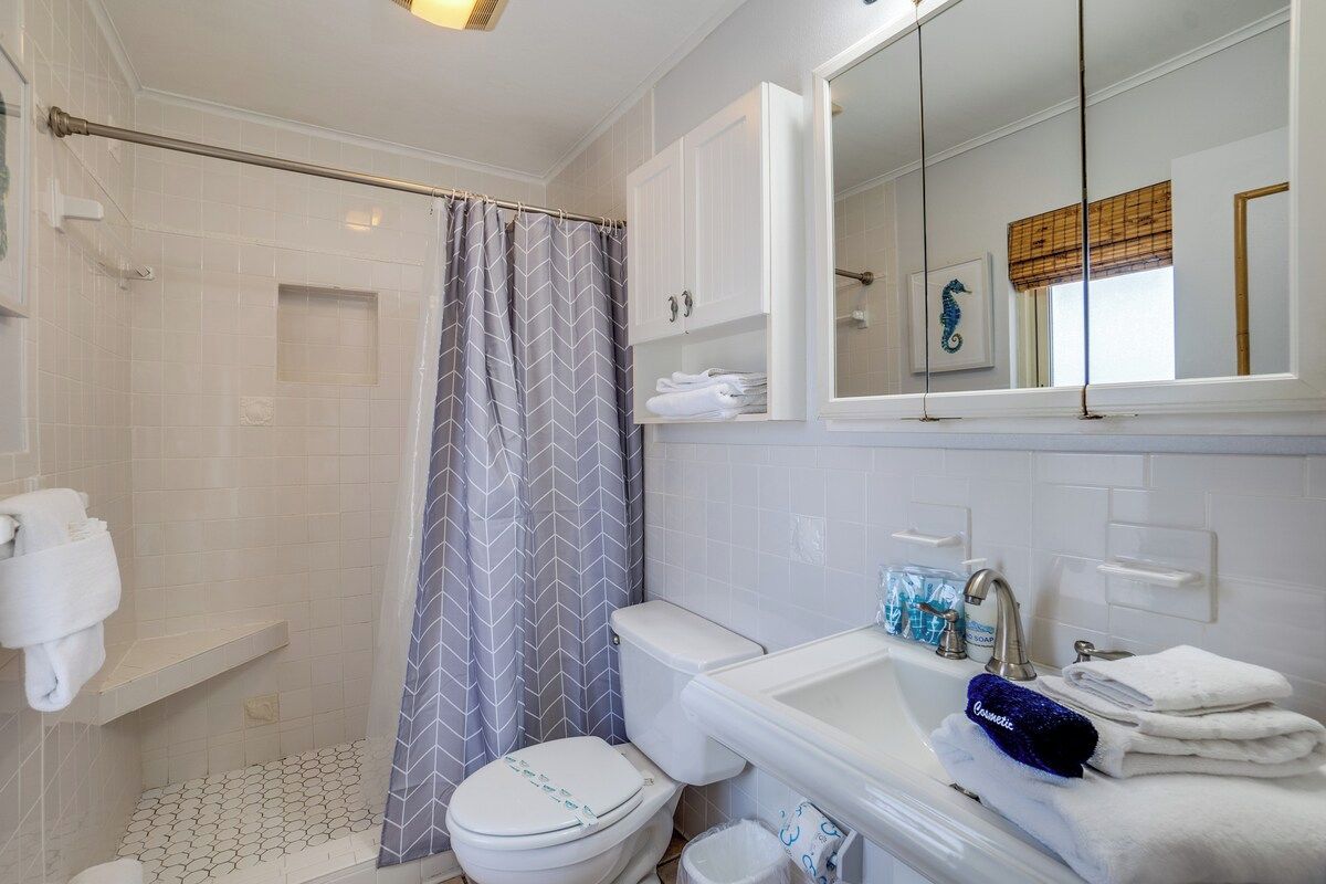 A bathroom with a shower, toilet, sink, and a mirror.