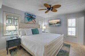 Ein Schlafzimmer mit einem Bett, Nachttischen, einem Deckenventilator und Kunstwerken an den Wänden.