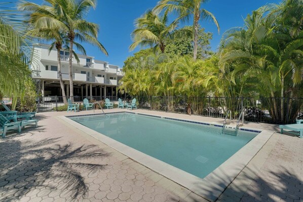 A swimming pool with lounge chairs and palm trees.