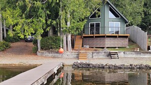 Een chalet met terras, een steiger en een vijver.