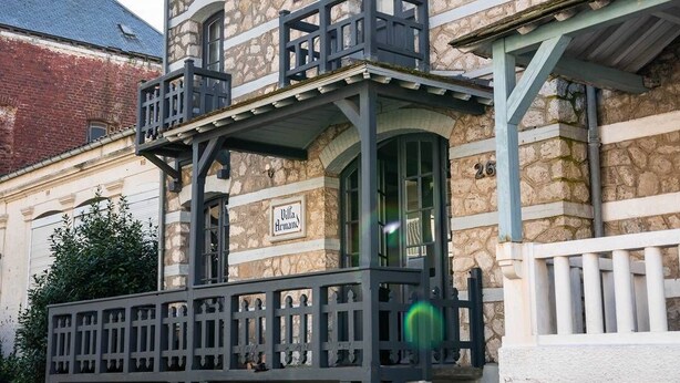 Un edificio de piedra con un balcón y un letrero que dice "Villa Hermand".