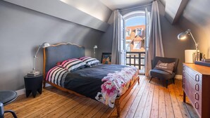 Un dormitorio con cama, escritorio, silla y ventana con cortinas.