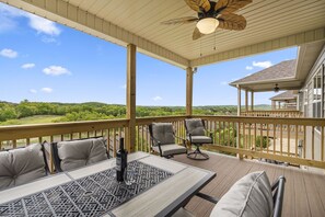 A covered outdoor deck with a table and chairs, overlooking a scenic landscape. - Gated Golf Community, Private Hot Tub, Arcade, Updated Kitchen & Free Tickets Near SDC (Branson West)