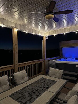 An outdoor deck with a ceiling fan, string lights, and a hot tub. - Gated Golf Community, Private Hot Tub, Arcade, Updated Kitchen & Free Tickets Near SDC (Branson West)
