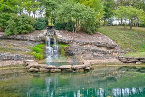 Un paisaje natural con una cascada, un estanque y abundante vegetación.
