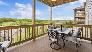 Una terrazza in legno con tavolo e sedie, affacciata su un paesaggio verdeggiante.