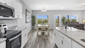 A modern kitchen with granite countertops, stainless steel appliances, and a dining area with a wooden table and chairs. - Stonebridge Resort Condo w Onsite Golf_Private Hot Tub_Outdoor Pool_Free Tickets (Branson West)