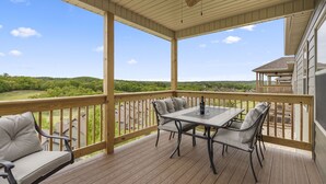 A covered outdoor deck with a table and chairs, overlooking a scenic landscape. - Stonebridge Resort Condo w Onsite Golf_Private Hot Tub_Outdoor Pool_Free Tickets (Branson West)