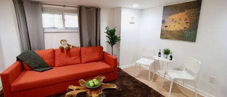 A living room with a red sofa, a coffee table with a plant, and a painting on the wall.