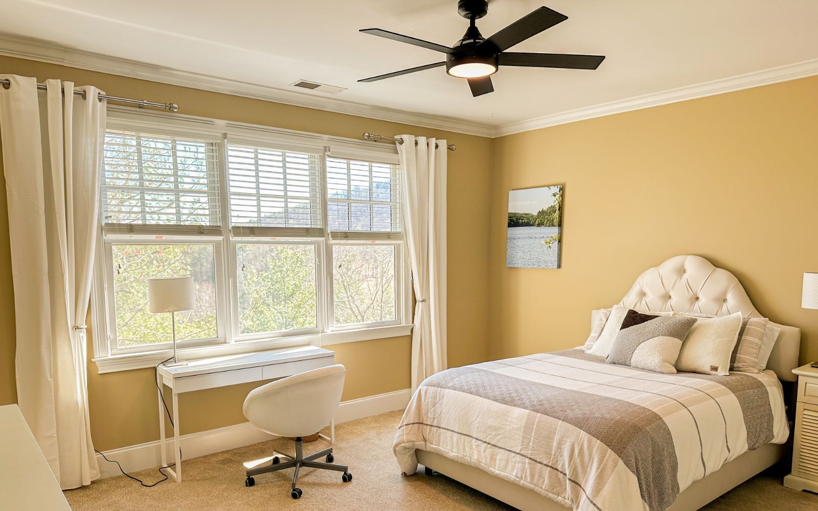 Une chambre à coucher comprenant un lit, un bureau, une chaise et un ventilateur de plafond.