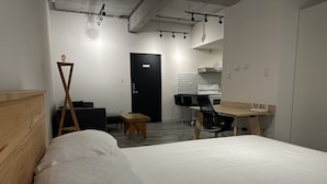Een moderne hotelkamer met een groot bed, een bureau met stoel, een klein tafeltje en een zwarte deur.