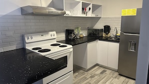 Een moderne keuken met een witte kookplaat, een zwart aanrecht en witte kastjes.