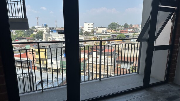 Een balkon met uitzicht op een stadsgezicht, met gebouwen en een heldere lucht.