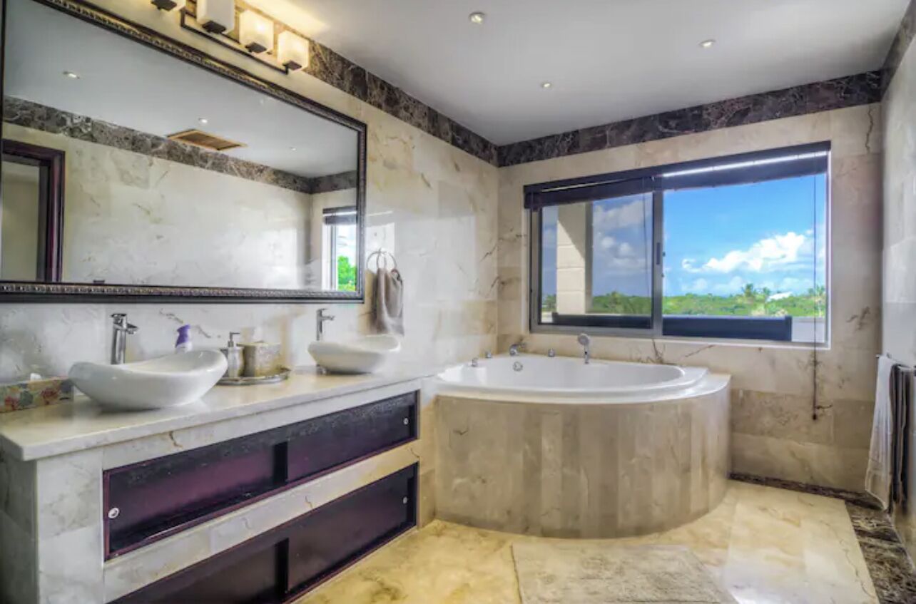 Ein modernes Badezimmer mit zwei Waschbecken, einer großen Badewanne und einem großen Spiegel.