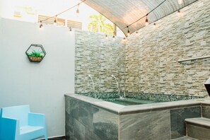 A spa area with a stone wall, a small pool, and a blue chair. - SUITE 103 - 4 PEOPLE (W PRIVATE POOL) (Cabo Rojo)
