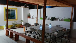 Une terrasse extérieure agrémentée d’une pergola en bois, d’une table à manger avec des chaises et de plantes en pot.