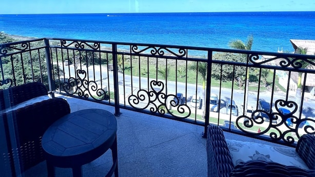 Un balcone con vista sull'oceano, un tavolo rotondo e un divano in vimini.