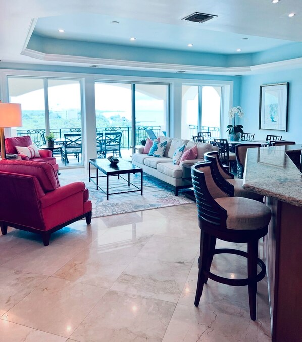 Un salón amplio con un sofá rojo, un sofá color crema y una zona de comedor con barra.