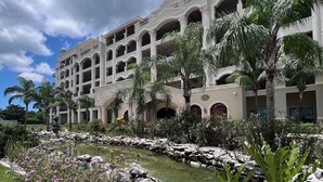 Un hotel con numerosi balconi, un cortile centrale con elemento d'acqua e vegetazione circostante.