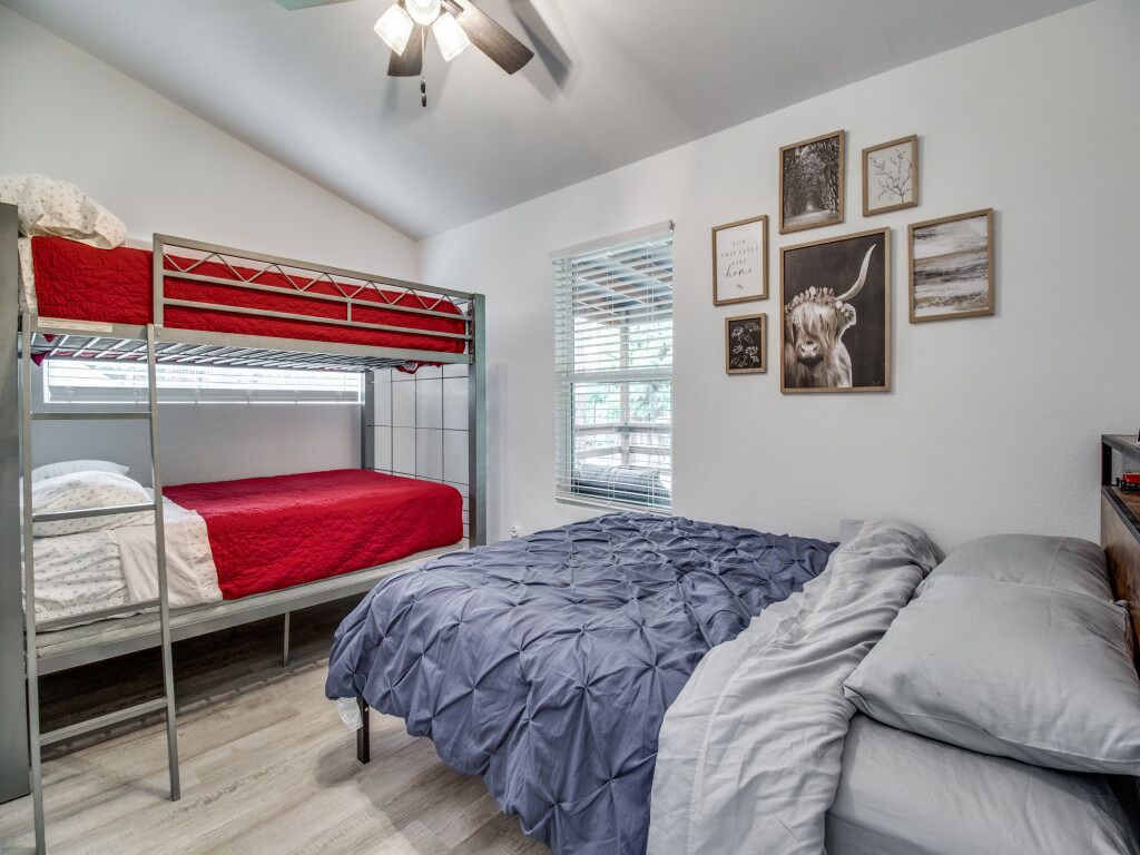 A dormitory room with bunk beds, a large bed, and a window with blinds.