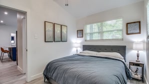 Een slaapkamer met een groot bed, een bureau en een stoel in de aangrenzende kamer.