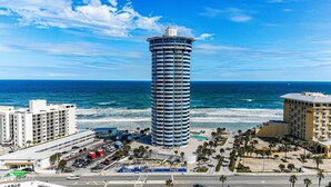 A tall hotel with a cylindrical shape, located near a beach with a view of the ocean.