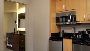 A modern kitchen with stainless steel appliances, wooden cabinets, and a black countertop. - Stay in Style at Elara Hilton's 2BR Suite During the Las Vegas Formula 1 Race. (Las Vegas)