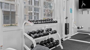 A gym with a rack of dumbbells, a bench, and a wall-mounted TV. - North Myrtle Beach Condo (North Myrtle Beach)