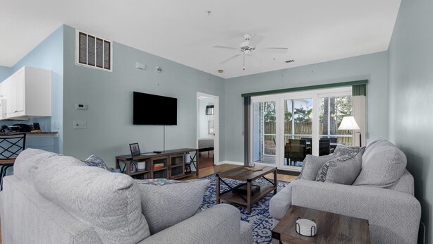A spacious living room with a gray sofa, a coffee table, and a TV mounted on the wall. - North Myrtle Beach Condo (North Myrtle Beach)