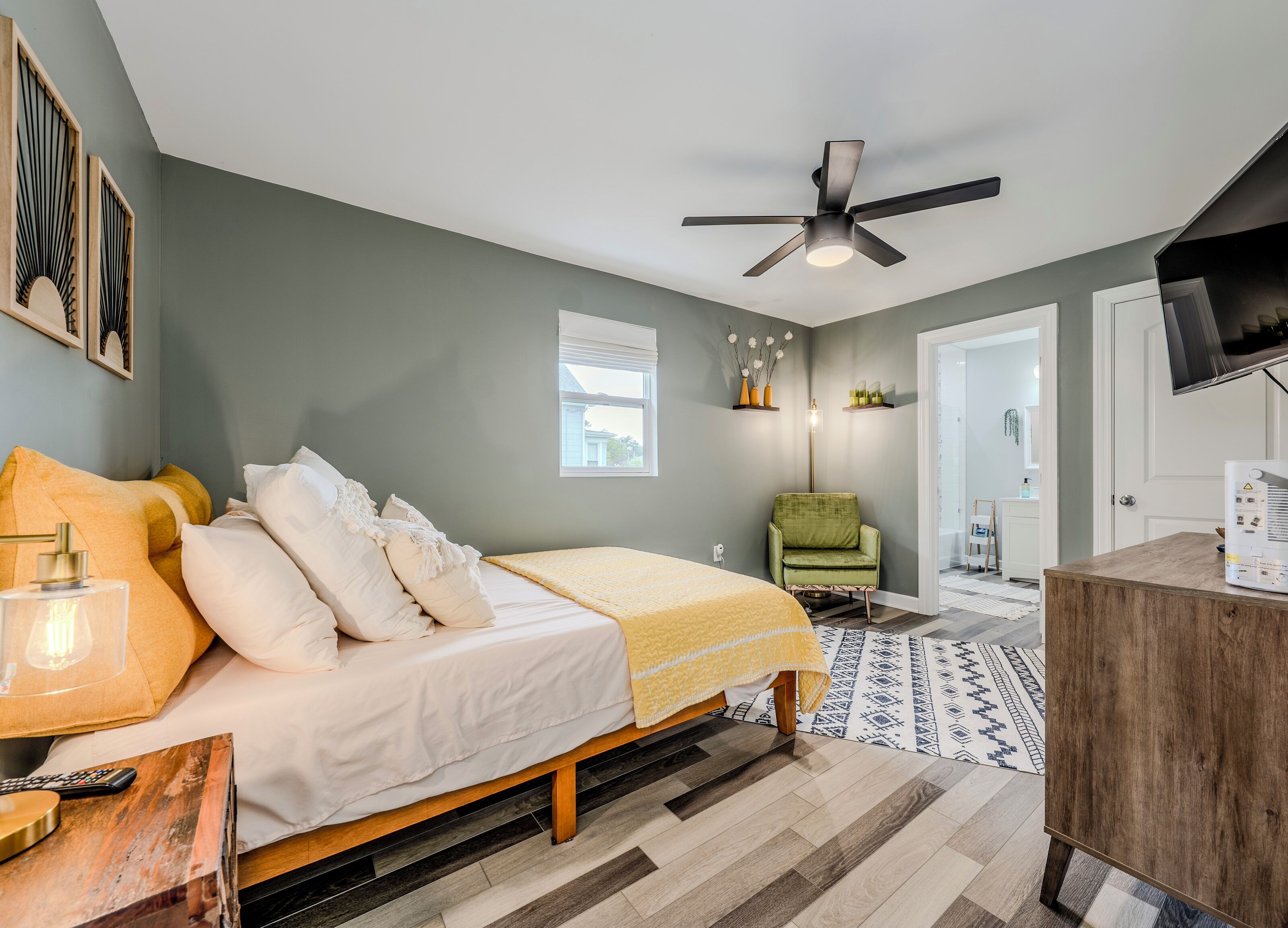 A modern bedroom with a bed, bedside table, lamp, and a ceiling fan.