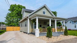 Una casa a un piano con portico, una recinzione in legno e un prato curato.