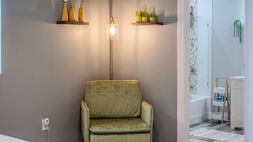 Relax in a cozy corner with a plush armchair and a serene view of the adjacent bathroom area.