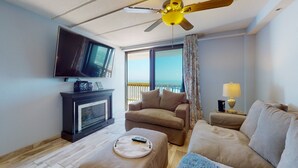 A living room with a TV, fireplace, sofa, and a balcony with a view.