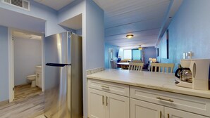 A modern kitchen with a stainless steel refrigerator, white cabinetry, and a coffee maker.