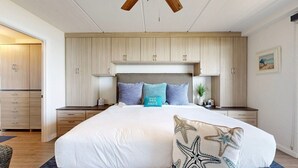 A bedroom with a large bed, wooden wardrobe, and a ceiling fan. - Ocean View, Shared Pool/Hot Tub, Boardwalk to Beach (Port Aransas)