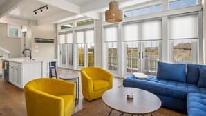 Amplia sala de estar con un sofá azul, sillones amarillos y una mesa de centro redonda.