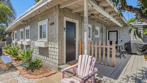 A small house with a porch, a covered patio, and a wooden chair. - 4 Beach Flats Sleeps 18 2Blks from Beach,Boardwalk,Sand,Surf (San Diego)