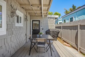 Un patio couvert avec une table et des chaises, une porte et un barbecue extérieur abrité.
