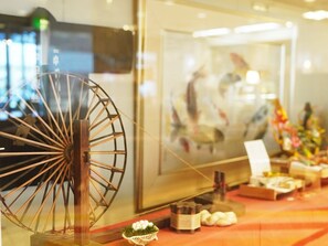 A traditional Japanese room with a wooden wheel, a framed painting, and a small table with items.