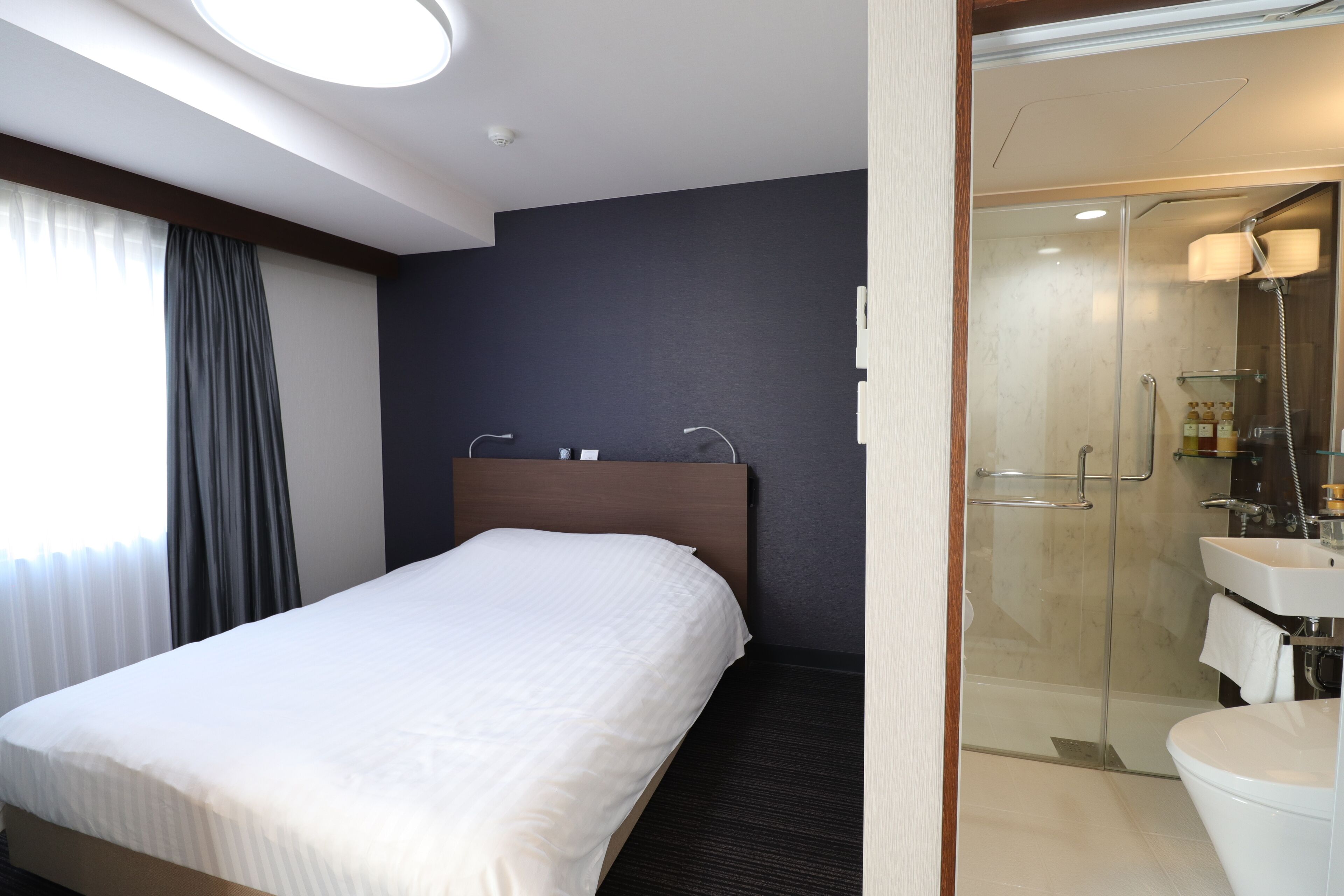 A hotel room with a bed, a shower, and a bathroom.