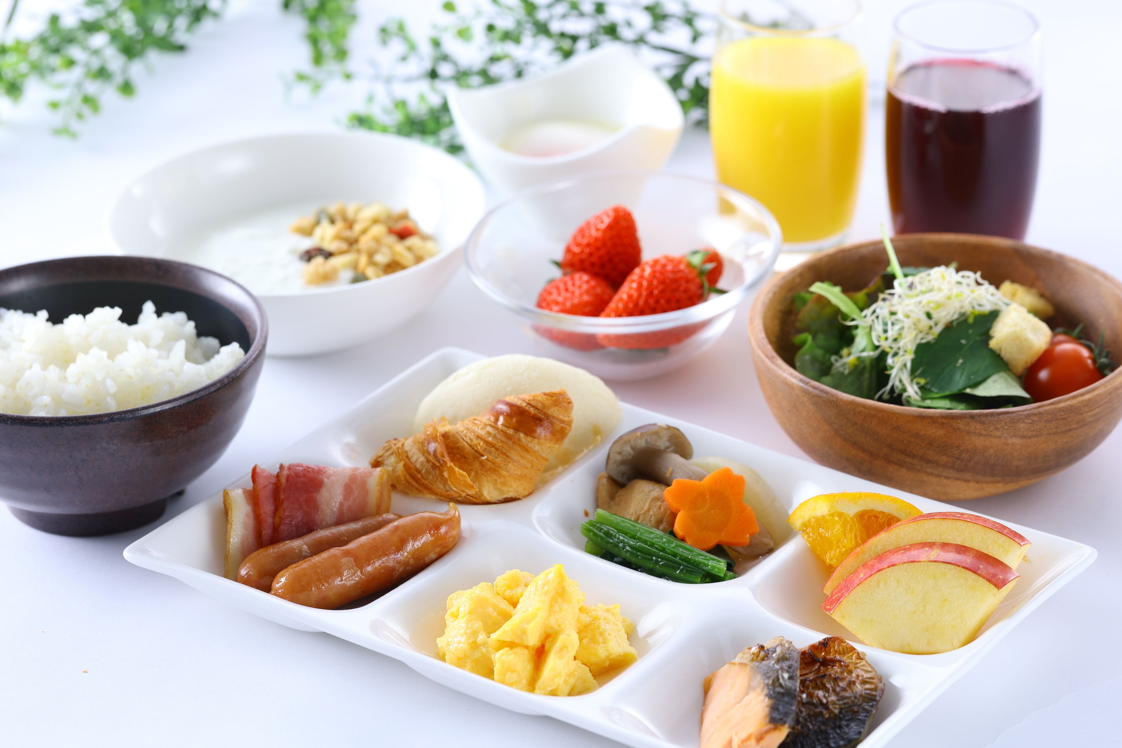 Una mesa de desayuno con diversos alimentos, como arroz, huevos, salchichas y frutas.